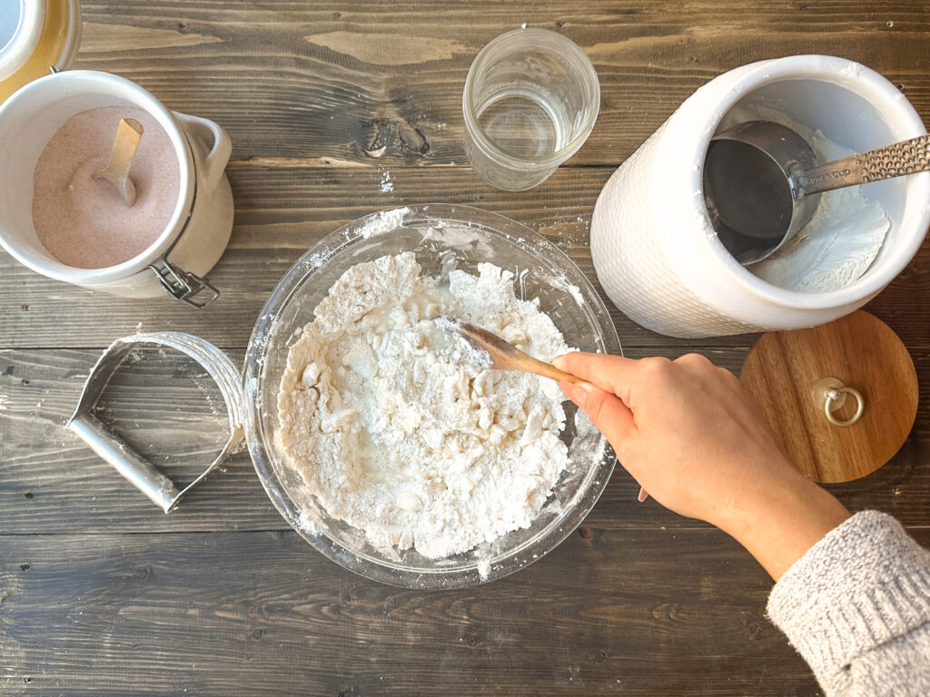 image showing how to make pie crust from scratch without using a food processor - mixing the dough using a wooden spoon