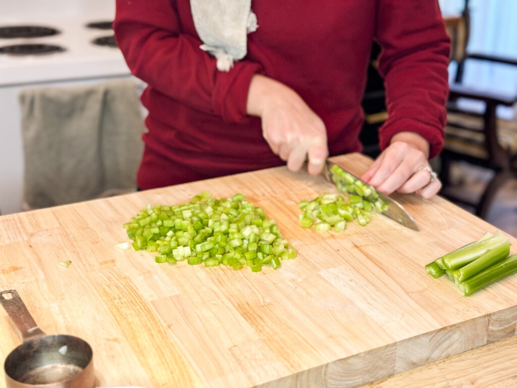 A woman chopping celery on a cutting board. 