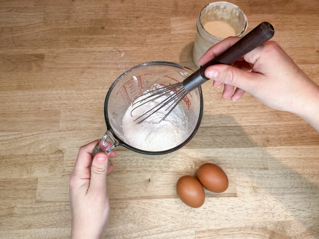 A woman's hand mixing together the dry ingredients of funnel cake batter.