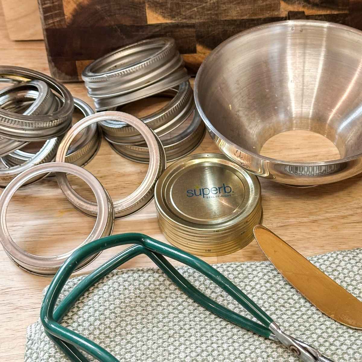 Canning supplies needed for preserving food: canning rings, gasket lids, canning funnel, and jar lifter.